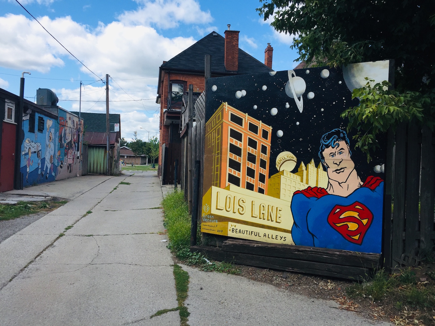 A mural of Superman in a paved alleyway