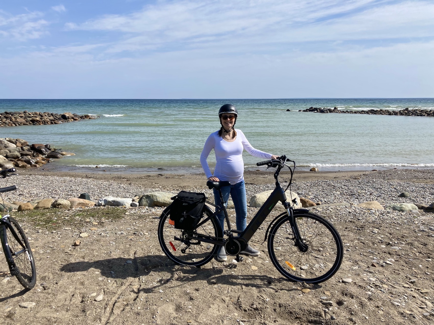 A photo of me standing with my e-bike on a rocky beach with Georgian Bay in the background.