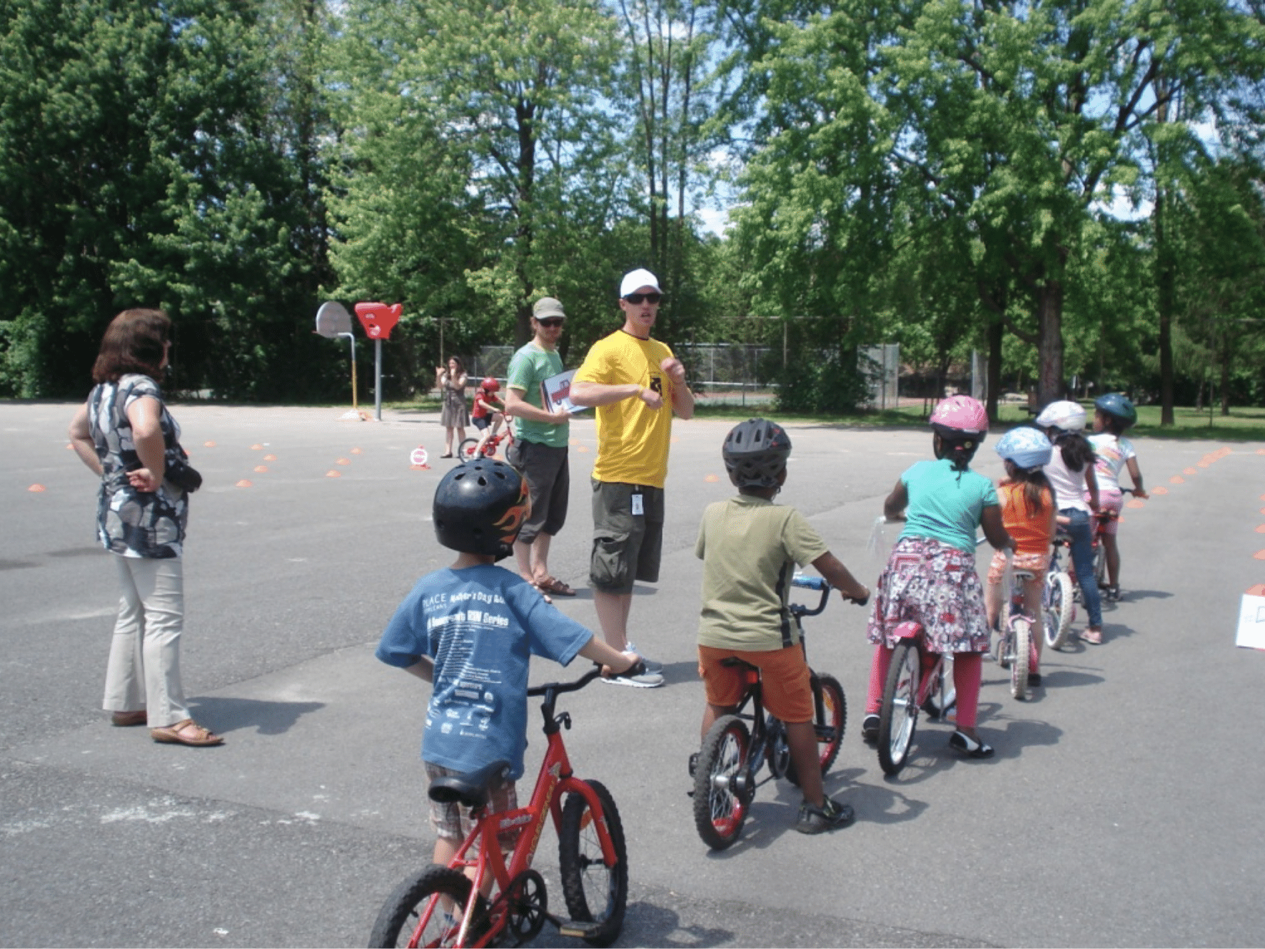 A group of elementary school students standing in line on their bicycles learning to ride in the school yard