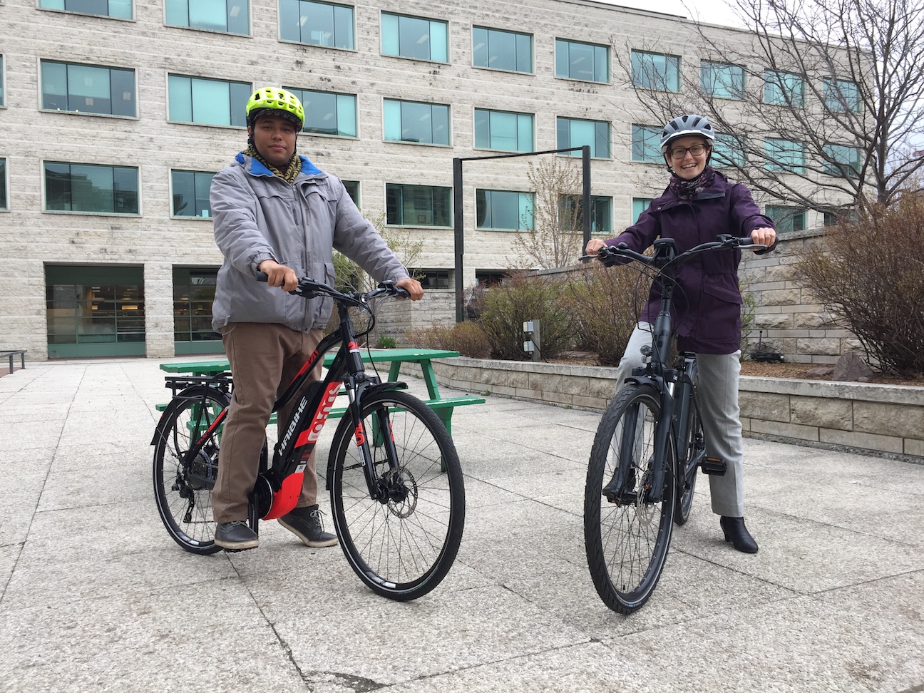 Jamie and Darnel standing on e-bikes outside Ottawa's City Hall