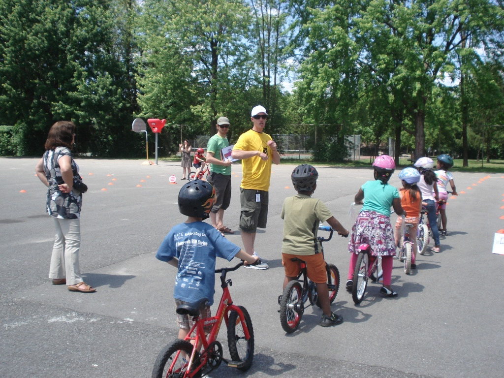 A group of elementary school children lined up on bicycles learning to ride bikes